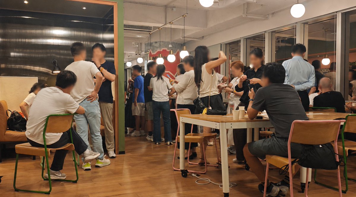 A lively crowd of attendees mingles at an indoor networking event, gathering around tables and chatting over food and drinks in a warmly lit venue with pendant lights and wooden floors. The casual, energetic atmosphere reflects the post's celebration of "Bitcoin, Beer & Friends 2026," where attendees connected to exchange ideas about building within the ecosystem.