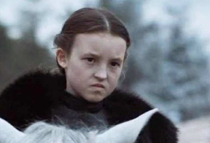 A young girl with braided hair and a fur-trimmed coat looks displeased in a snowy outdoor setting, appearing to be a still from a film.
