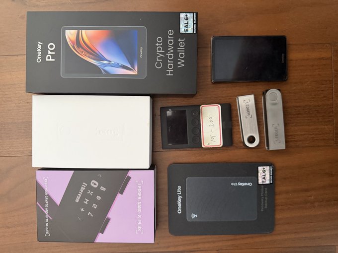 An overhead photo of various cryptocurrency hardware wallets and their packaging, including OneKey Pro, OneKey Lite, and Ledger Nano S Plus.
