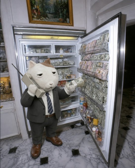 An anthropomorphic white cat wearing a gray business suit and tie holds a brick phone and cash while standing in front of an open refrigerator filled with stacks of money and bottles.