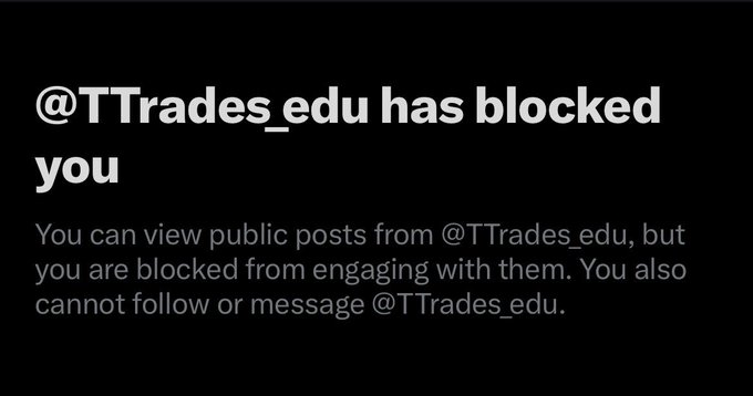 The image shows a Twitter/X notification stating "@TTrades_edu has blocked you," with the account noting the user can still view public posts but cannot engage with them. The post treats being blocked by the trading account as a "badge of honour," implying the user's open-source trading indicator code has drawn criticism from the proprietary indicator seller.