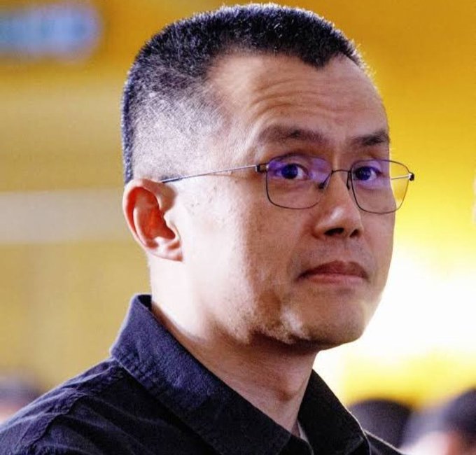 A man with short-cropped hair and rectangular glasses looks off to the side, representing Changpeng Zhao (CZ), the Binance founder referenced in the post about his prediction of a potential 2026 crypto supercycle.