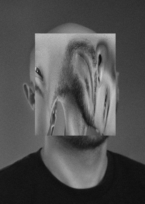 A black-and-white photo of a person with their face obscured by a rectangular distortion glitch effect, creating a surreal, fragmented appearance against a dark gray background.
