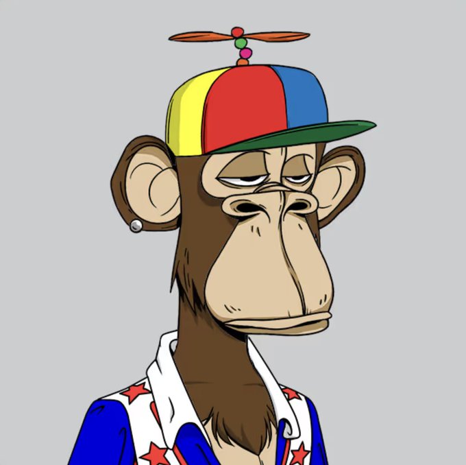 The image features a cartoon monkey wearing a colorful hat with red, yellow, green, blue, and orange colors. The monkey also has a star-patterned shirt and a blue jacket. The background of the image is gray, which contrasts with the vibrant colors of the monkey's outfit. The caption below the image reads: "Proud to be a member of @BoredApeYC".