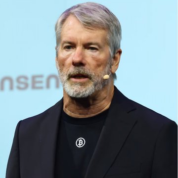The image shows Michael Saylor, executive chairman of Strategy (formerly MicroStrategy), speaking at an event with a headset microphone. His appearance accompanies the post's discussion of how STRC, Strategy's perpetual preferred stock designed to trade near $100, is experiencing a dangerous feedback loop in its Bitcoin accumulation mechanism.