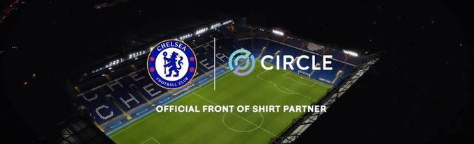 An aerial nighttime view of a soccer stadium featuring the Chelsea Football Club crest alongside the Circle logo, with text reading 'OFFICIAL FRONT OF SHIRT PARTNER'.