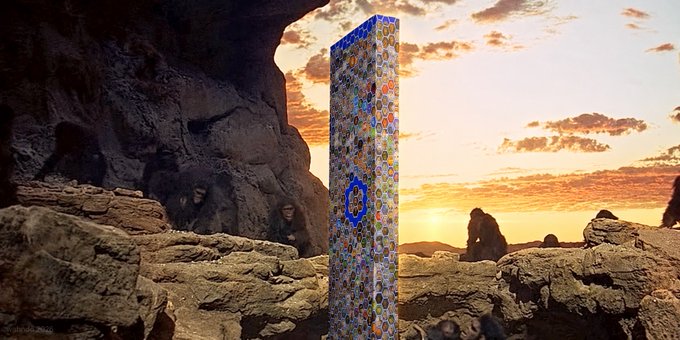 A prehistoric landscape at sunset with a colorful, patterned obelisk-like monument standing among rocks and cave-dwelling figures, including what appears to be early hominids.