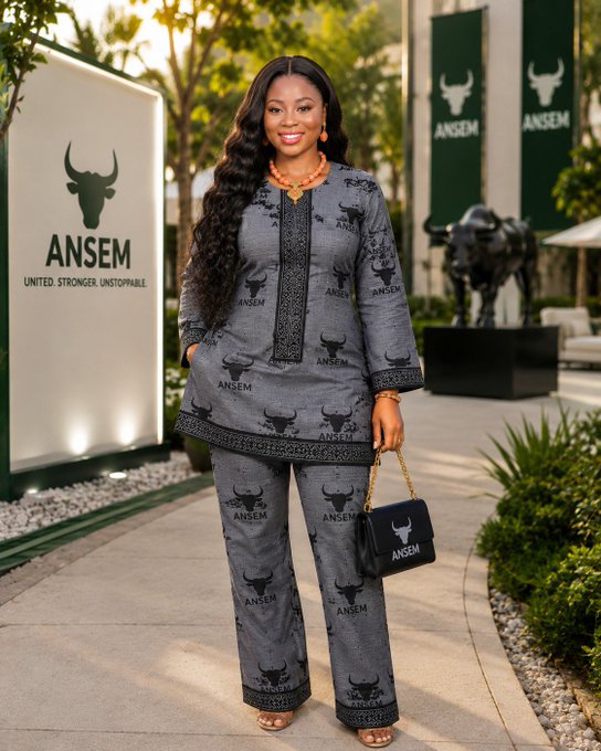 A woman poses in front of an ANSEM sign and banners, wearing matching ANSEM patterned clothing and carrying an ANSEM handbag, all displaying the ANSEM bull logo. This imagery directly supports the post's message about believing in the $ANSEM brand, its community, and its founder, @blknoiz, as it visually represents the brand's presence and unity.