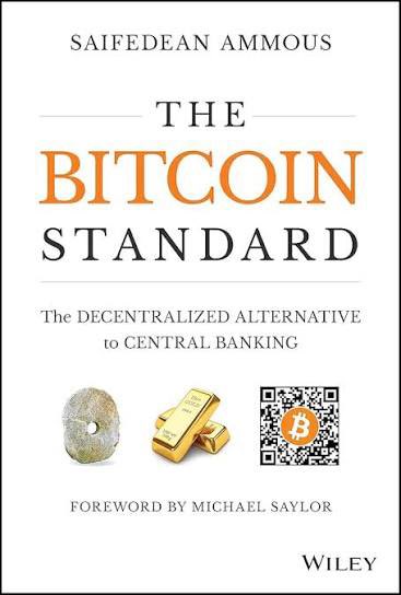 The image shows the book cover of "The Bitcoin Standard: The Decentralized Alternative to Central Banking" by Saifedean Ammous, with a foreword by Michael Saylor, published by Wiley. The cover features imagery of a stone, gold bars, and a Bitcoin QR code, which the post references as the author is rereading this influential Bitcoin economics book for the second time.