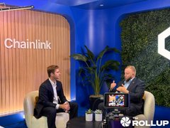 Two men sit in chairs on a set with a "Chainlink" sign, conducting an interview branded with the "ROLLUP" logo.