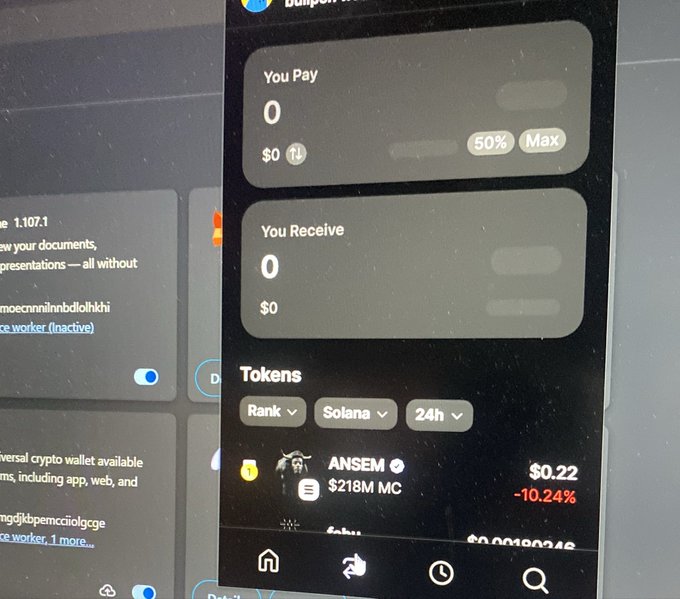 A photograph of a computer screen displaying a cryptocurrency swap interface with "You Pay" and "You Receive" both at $0, and a Tokens list showing "ANSEM" with a market cap of $218M and a price of $0.22 (-10.24%).