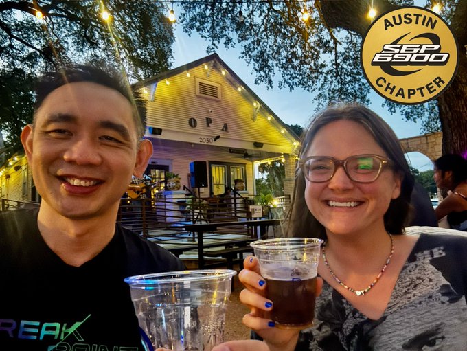A smiling couple takes a selfie while holding plastic cups of beer, with a logo in the top right corner reading 'AUSTIN SS990 CHAPTER'.