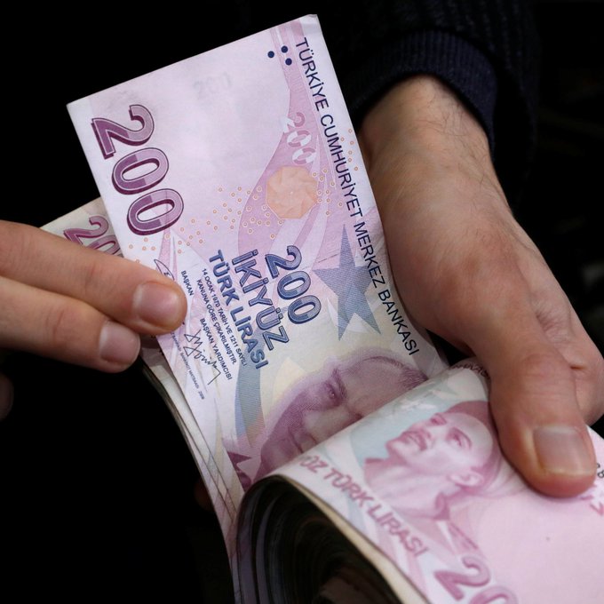 A pair of hands counts Turkish 200 lira banknotes featuring the portrait of Mustafa Kemal Atatürk, with text reading 'TÜRKİYE CUMHURİYET MERKEZ BANKASI' (Central Bank of the Republic of Turkey).