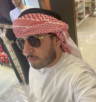 A man wearing traditional Gulf attire (white thobe and red-checkered keffiyeh) with sunglasses takes a selfie inside what appears to be a shop. The post's "ALERTA MAXIMA!!" caption suggests an urgent warning or alert, though the image itself doesn't display any related text or identifying information.