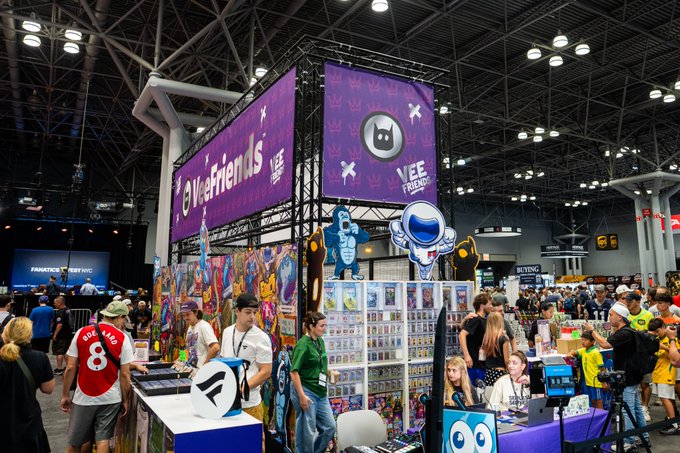 A bustling Fanatics Fest convention floor features a prominent purple VeeFriends booth (with "VEE FRIENDS" branding) displaying colorful character artwork and trading cards, where fans gather as Day 3 of the event gets underway.