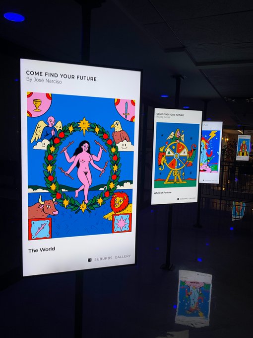 An art gallery display titled "COME FIND YOUR FUTURE By José Narciso" features illuminated signs of tarot cards, with "The World" prominent in the foreground and "Wheel of Fortune" visible behind, presented by Suburbs Gallery.