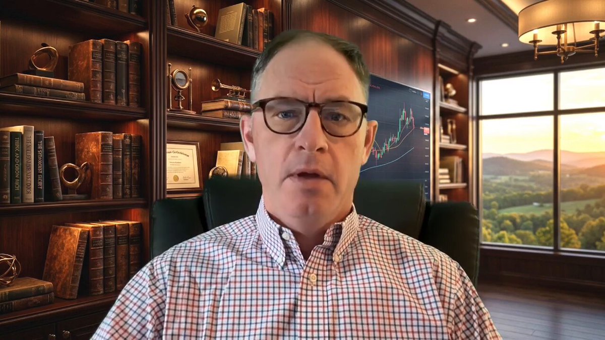 The image shows a man sitting in an office chair, wearing glasses and looking at the camera with a serious expression. Behind him are bookshelves filled with various books, suggesting that he might be working or studying in this space. The caption of the image reads "Wealthy Habits for XRP Holders: My 2026 Success Playbook Watch The Full Youtube Video Here: youtu.be/MHXNP_VtQJY". This implies that the man is likely discussing financial matters related to cryptocurrency, specifically XRP, and sharing his knowledge or experiences with others who are interested in this topic.