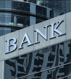Photograph of a modern glass building exterior with the word 'BANK' displayed in large silver letters on the facade.