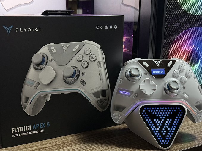A silver 'FLYDIGI APEX 5 ELITE GAMING CONTROLLER' sits next to its black product box, featuring RGB lighting and a triangular dot-matrix display showing a question mark.