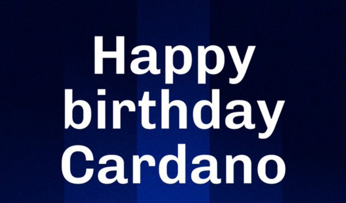 White text on a dark blue striped background reading 'Happy birthday Cardano'.