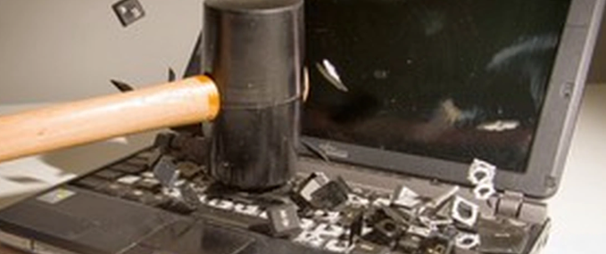 A sledgehammer smashes a laptop keyboard into shattered pieces, symbolizing the frustrated and defeated departure of a crypto investor who liquidated his entire portfolio after losing hope.