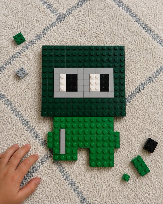 A child's hand reaches toward a LEGO build of a green, square-headed character with big pixelated eyes, set on a patterned carpet with loose bricks scattered around, tying into the post's playful competition announcement on @base to grow the prize pool.