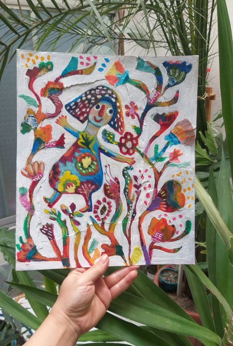 A hand holds up a vibrant, colorful painting featuring a whimsical figure with flowing hair surrounded by floral and abstract motifs, displayed against a backdrop of green plants—celebrating a successful sale to collector @Karanpal25 as noted in the caption.