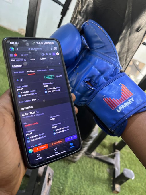 A hand at the gym holds a smartphone displaying a Meteora liquidity position with $99.67 in fees and a $84.87 total liquidity for the SOL/USDC pool, while a blue "LP Army" boxing glove rests on the leg nearby—visually reinforcing the post's message about seamlessly LPing between workout sets with help from @met_lparmy.