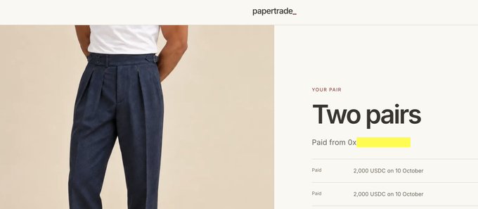 A webpage screenshot showing 'papertrade_' featuring dark blue pleated trousers priced at 2,000 USDC each, with the title 'Two pairs' and a yellow-redacted address.