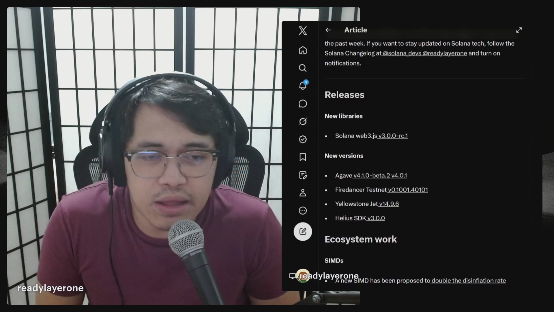 In the image, a man wearing glasses is sitting at a computer with headphones on his head. He appears to be engaged in a video call or streaming session, as indicated by the presence of a microphone attached to the computer screen. The focus of the image is on the man and his interaction with the content displayed on the screen.