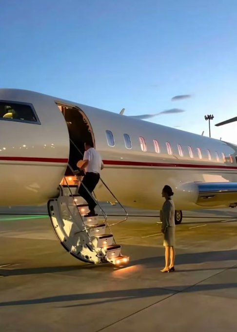 A person boarding a plane via a private airstair, where another person is holding a yellow hand fan on the tarmac at an airport.