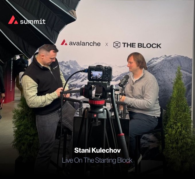 Two men conduct an interview at the Avalanche Summit, with text reading 'Stani Kulechov Live On The Starting Block' and 'avalanche x THE BLOCK' in the background.