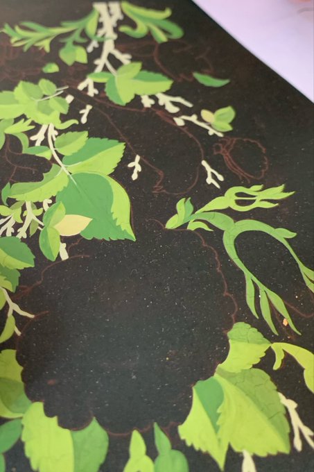 A close-up view of a black surface decorated with green paper or fabric leaves and stems, featuring a scalloped edge cutout.