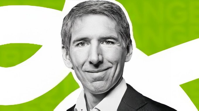 A black and white portrait photo of a smiling middle-aged man with short hair, set against a bright green and white graphic background.