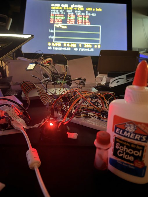 A Raspberry Pi project tangled in rainbow-colored jumper wires sits next to a glowing red LED and a bottle of Elmer's School Glue, while a monitor in the background displays a "BLOCK CACHE" interface showing "0.04" and "(65) x left." The chaotic DIY hardware setup whimsically captures the messy, glue-it-together spirit of building blockchain experiments—suggesting that taming decentralized tech often requires literal Elmer's and a lot of trial-and-error bloodshed.