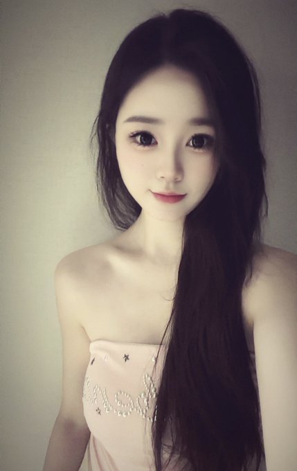 The image shows a young woman with long dark hair and soft makeup wearing a strapless light pink dress with embellishments, smiling softly at the camera. The caption should reflect that this post is playfully redirecting attention away from cryptocurrency discussions to focus on the photo, though no abs are visible in this particular image—just a graceful portrait highlighting her elegant appearance.