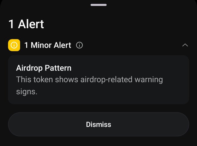 A mobile app alert displays "1 Alert" with a "1 Minor Alert" noting an "Airdrop Pattern" warning, indicating the token shows airdrop-related warning signs, with a Dismiss button below—suggesting caution about potential token incentives tied to the platform being discussed.