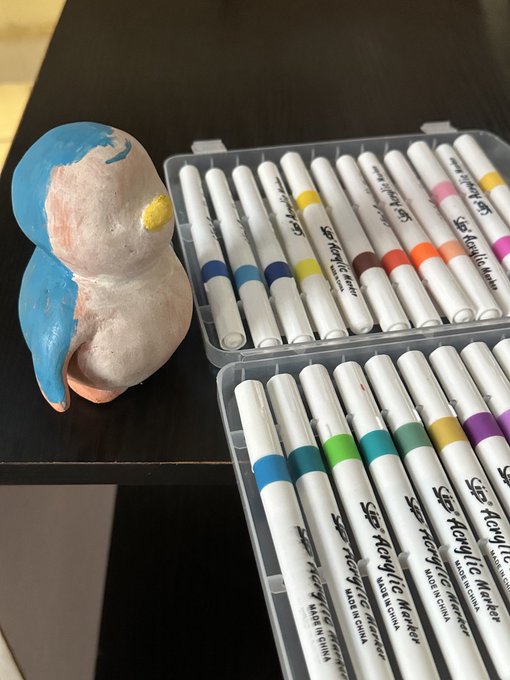 The image shows a partially painted clay sculpture of a penguin next to a set of "Sip Acrylic Marker" pens, ready for its finishing touches. The post likely refers to the act of painting the sculpture of the @pudgypenguins.
