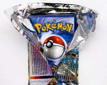 An opened foil booster pack from the Pokémon Trading Card Game lies flat, revealing a glimpse of the colorful cards and back insert inside.