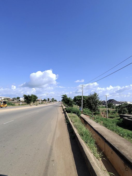 A clear, sunny day along a quiet roadside lined with greenery and power lines, with a few vehicles visible in the distance, perfectly capturing the bright, peaceful Saturday morning vibe described in the post.