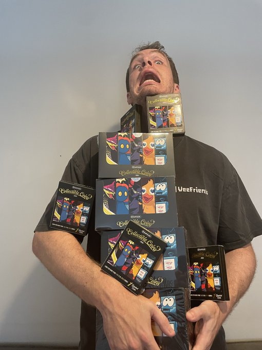A man with an exaggerated shocked expression, his torso covered in multiple boxes of "Garten of Banban" Bandai trading card game merchandise.