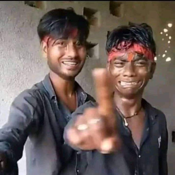 Low-resolution video still of two young men with red stains on their faces and clothes, one pointing aggressively at the camera with a wide grin.