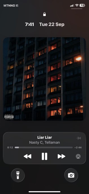 An iPhone lock screen displaying the music player for the song 'Liar Liar' by Nasty C and Tellaman, with album art showing a high-rise apartment building at sunset.