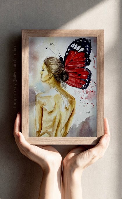 Hands holding a framed watercolor painting depicting a nude woman from the back with large red and black butterfly wings, credited to '@silverbirchstudio'.