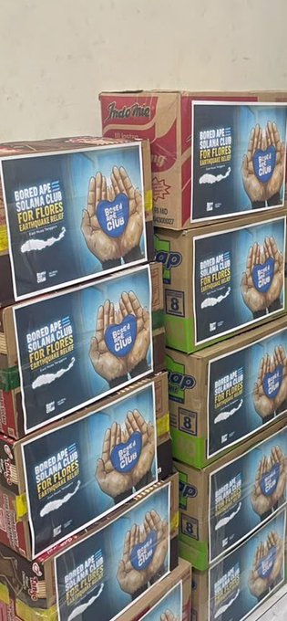 Stacked cardboard boxes of Inakome brand ramen with labels reading 'BORED APE SOLANA CLUB FOR FLOPES EATING MISO' featuring a blue ape logo held in hands.