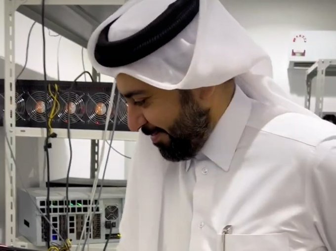 A man in traditional attire is shown looking at servers, likely part of the SidraChain infrastructure undergoing maintenance. The post mentions "SidraChain App" and "E-Express Community" in the context of ongoing improvements.