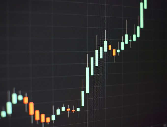 A close-up of a cryptocurrency candlestick chart shows an upward price trend with green (bullish) and orange (bearish) candles against a dark grid background. The image visually represents the question of which altcoin—$ETH or $SOL—will replicate this bullish breakout pattern next.