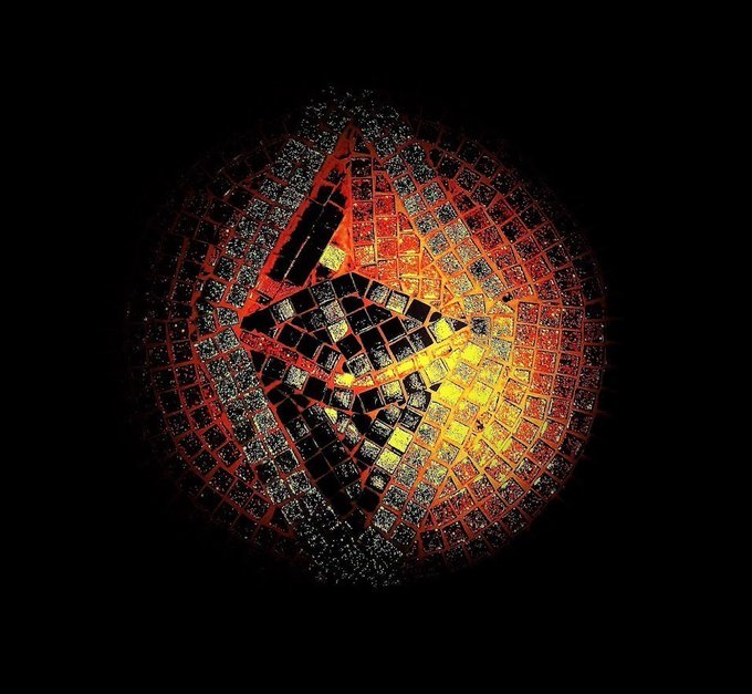 A stylized image of a cracked disco ball against a black background, illuminated with red and yellow light that creates a fiery glow within the mirrored facets.