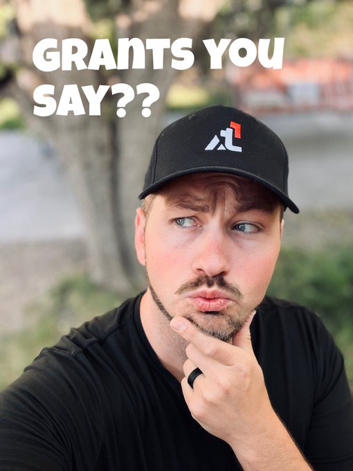 A man wearing a black 'Alt' branded cap with a confused or skeptical expression (hand on chin), accompanied by the text 'GRANTS YOU SAY??'.
