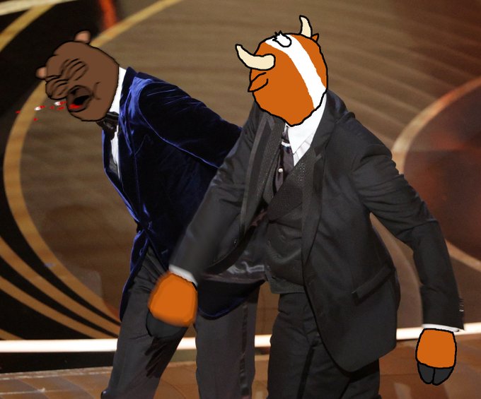 An edited image showing a man in a tuxedo with a cartoon hippo head and orange boxing gloves standing next to another man whose face appears distorted.